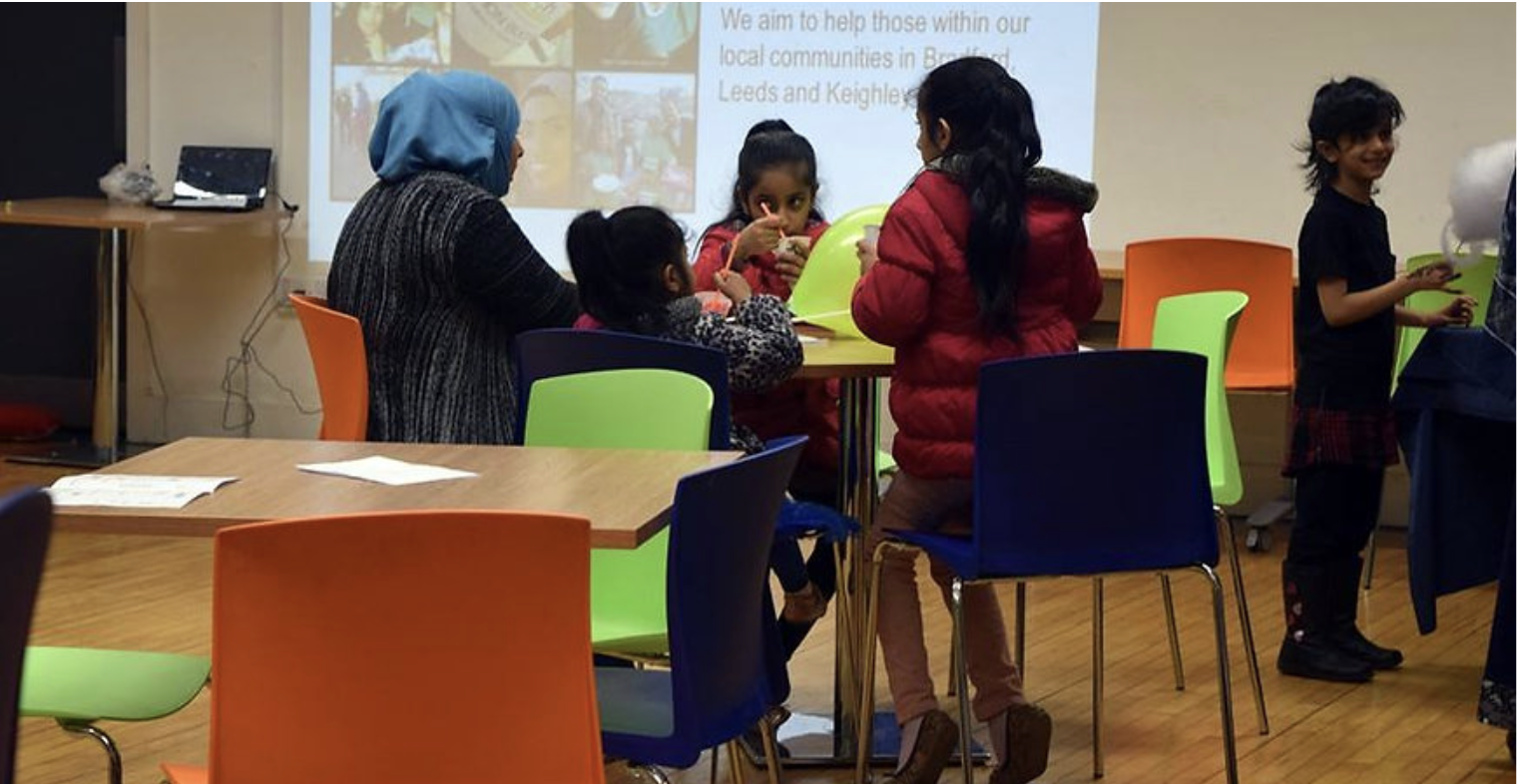 A woman and three children sitting at a round table indoors.